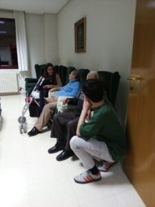 Jóvenes acompañan a personas mayores sentadas en una residencia