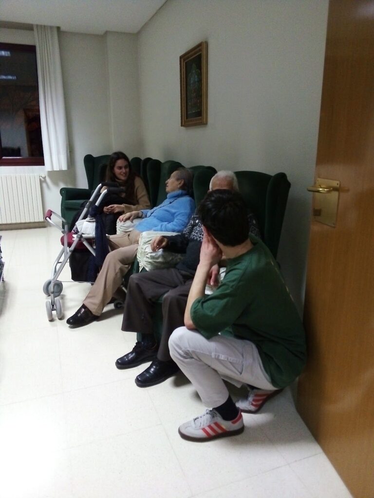 Jóvenes acompañan a personas mayores sentadas en una residencia
